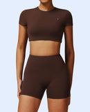Woman wearing brown ORU Hollow Back Cropped Top and matching shorts, slim fit activewear with seamless comfort