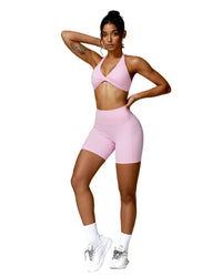 Woman wearing pink ORU Mika halter sports bra with halter neck support and matching shorts, styled for fitness or casual wear