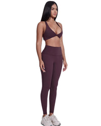 Woman wearing purple ORU LEGACY SPORTS BRA with wide straps and matching leggings, showcasing seamless, breathable, quick-drying fabric and twist folding front design.