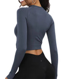 Back view of woman wearing slim fit ORU cropped long sleeve top with thumb hole cuffs, designed for running and training