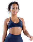 Back view of a woman wearing a navy seamless ORU SPARK SPORTS BRA with strappy back and light support underband.