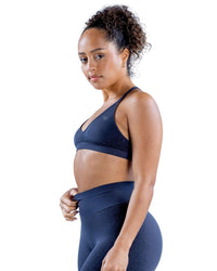Back view of a woman wearing a navy seamless ORU SPARK SPORTS BRA with strappy back and light support underband.