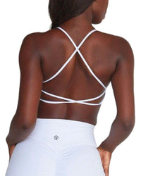 Back view of a woman wearing a white ORU CROSSOVER SPORTS BRA with crisscross straps and ruched detailing on the high-waisted bottom